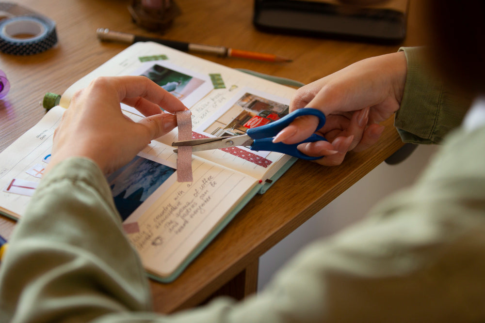Crafter cutting washi tape and applying it to a journal page for creative paper crafting