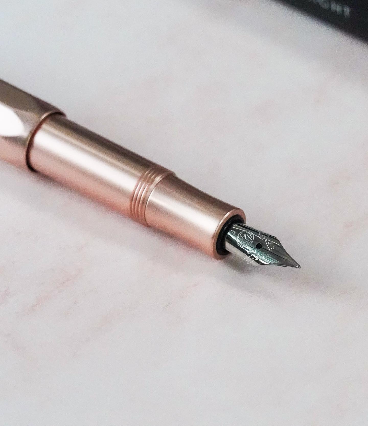Close-up of an uncapped rose gold fountain pen nib and section, ready for a basic water rinse and cleaning routine.